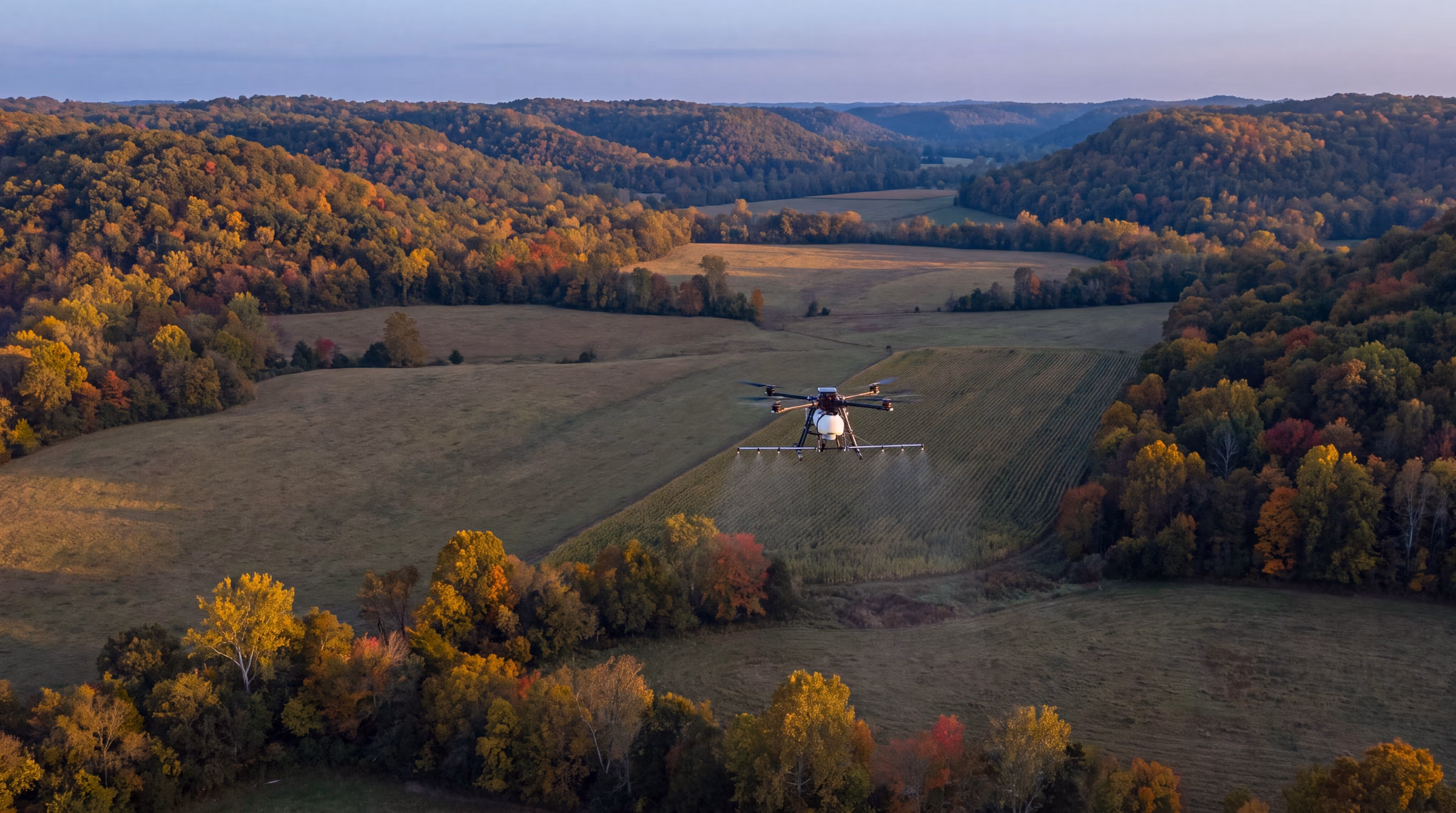 Illustrative: an unbranded spray drone over a row-crop field in an Ozark valley at blue hour